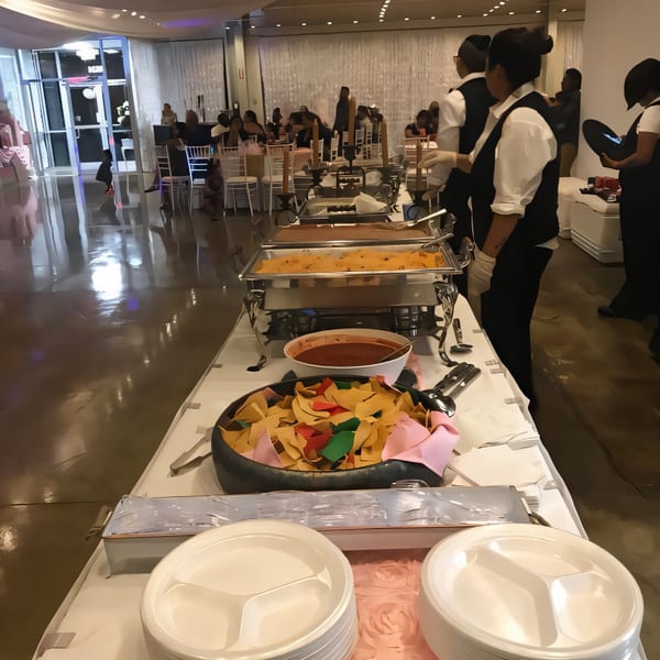Buffet line with Mexican food, including chips, salsa, and hot dishes, served by staff.