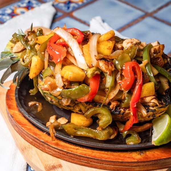 Pineapple fajitas with chicken, bell peppers, and onions, served on a sizzling platter.